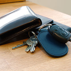 A set of car keys, house keys and a wallet on top of a desk.