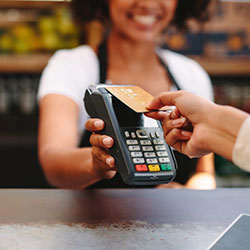 A saleswoman holding the payment machine while another woman taps it to pay for her purchase.