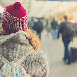 The back of a woman wearing a toque and winter jacket while walking to the gate at the airport.