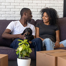 A young couple moving into their new apartment with a puppy.
